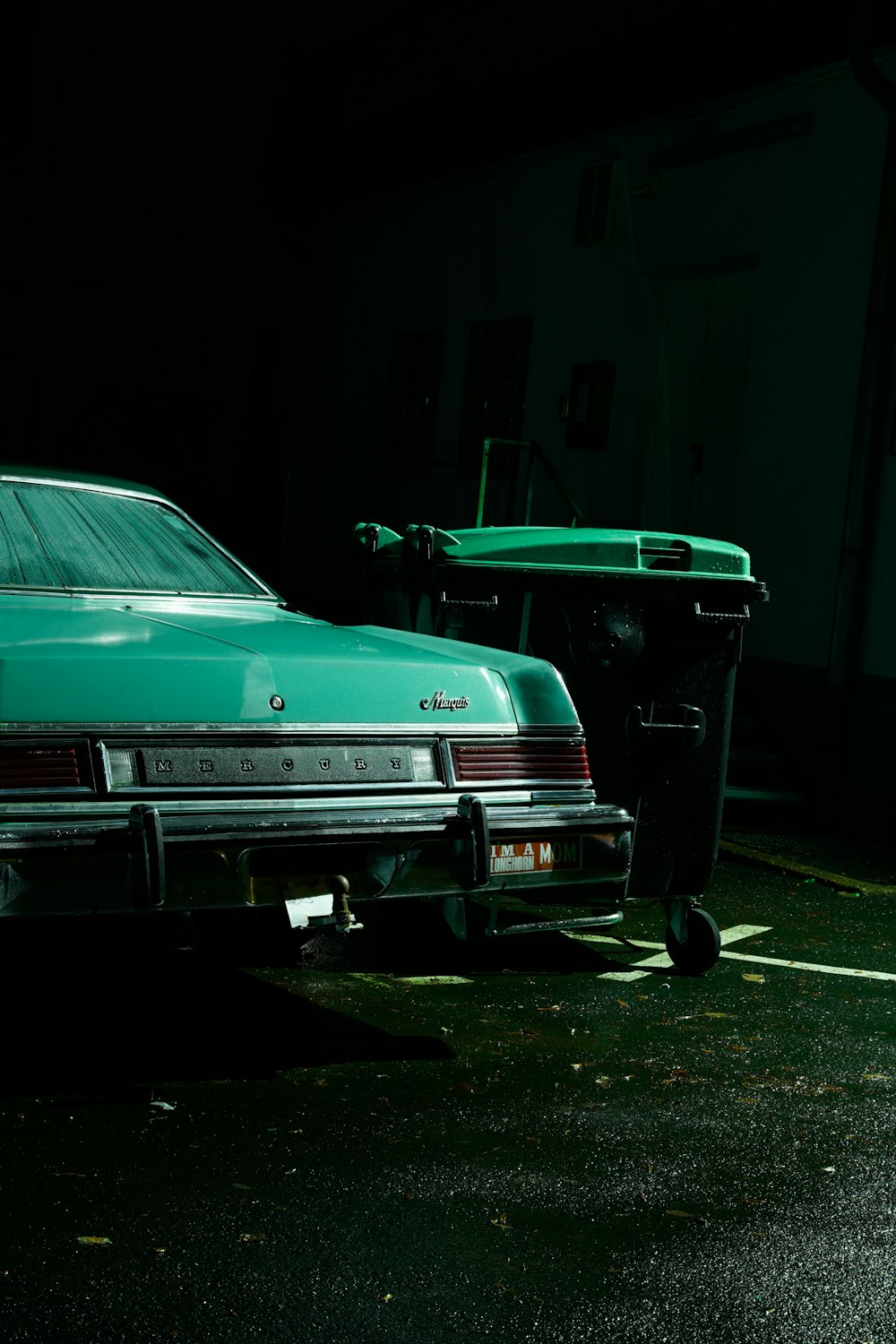 a green car parked in a parking lot next to a trash can