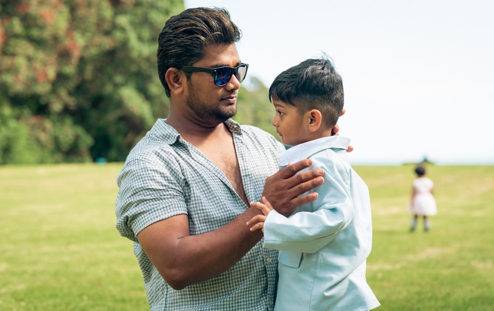 a man holding a small boy in a field