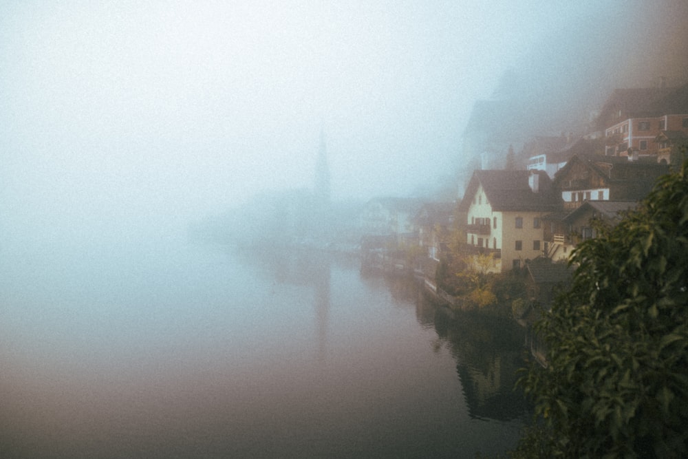 a foggy river with houses on the shore