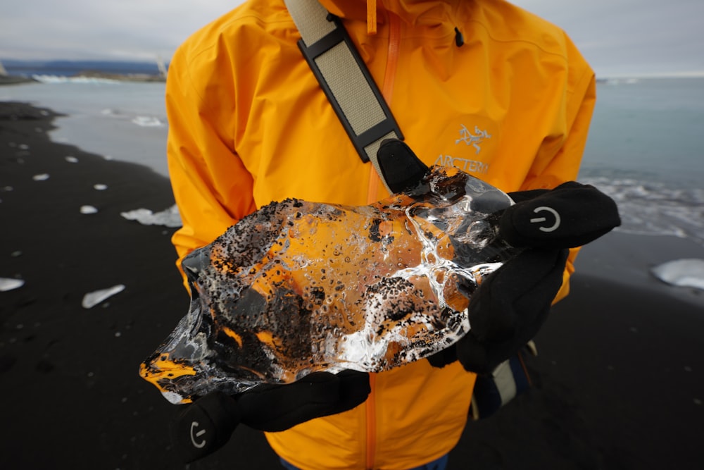 a man in a yellow jacket holding a piece of metal