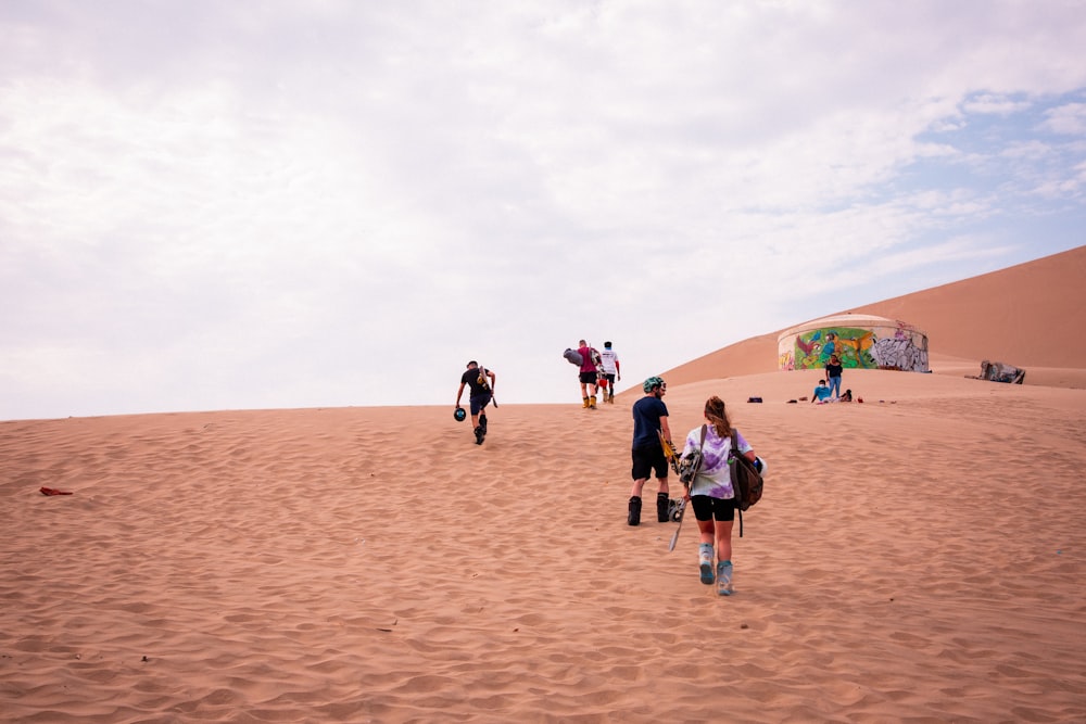 um grupo de pessoas subindo uma duna de areia