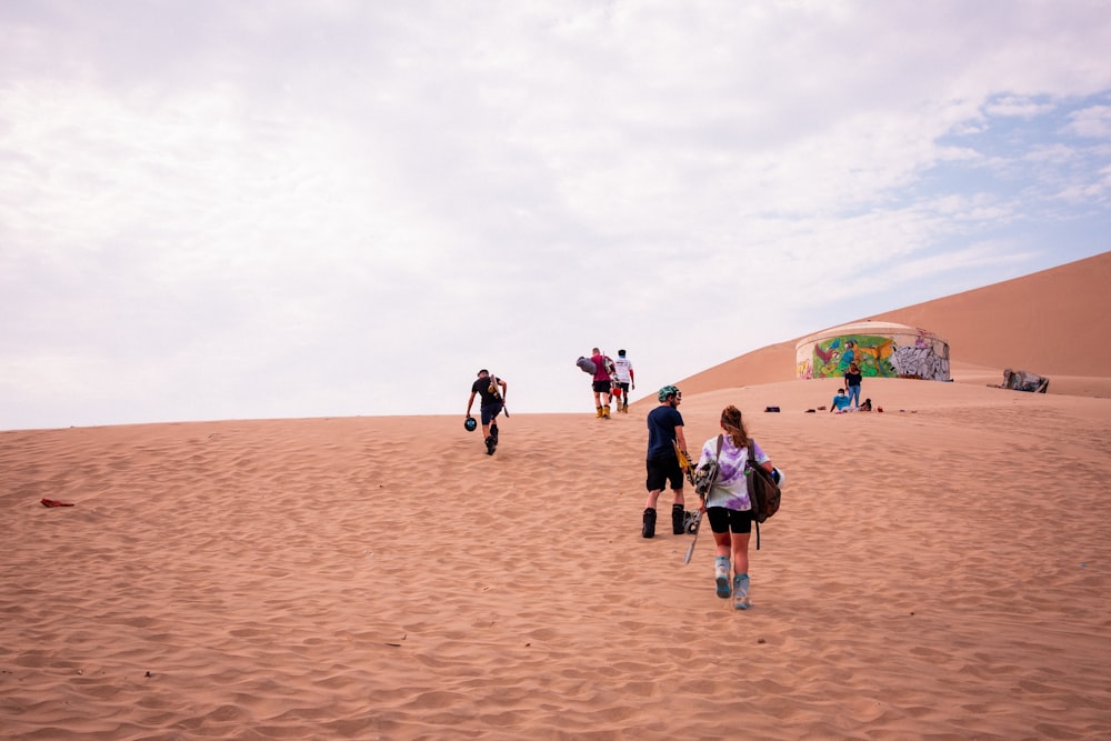 a group of people walking up a sand dune