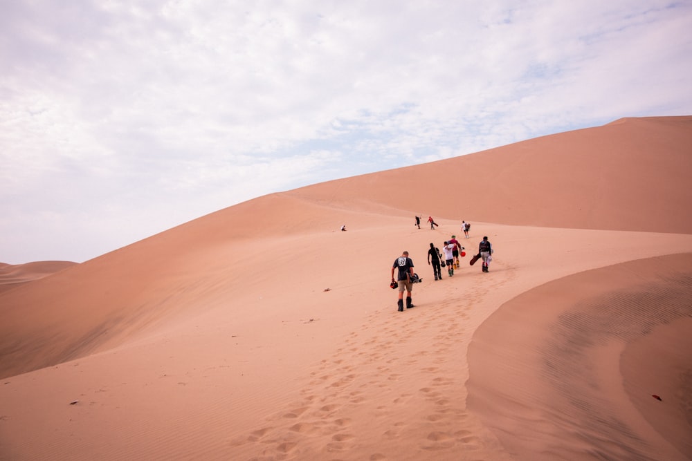 a group of people walking up a sand dune