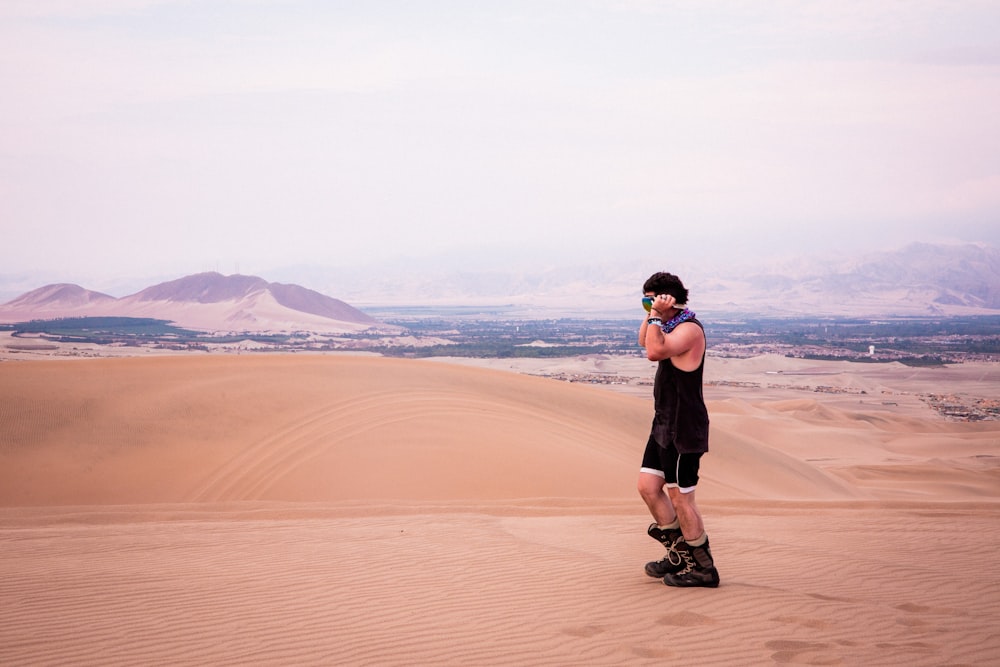 a man standing on top of a sand dune