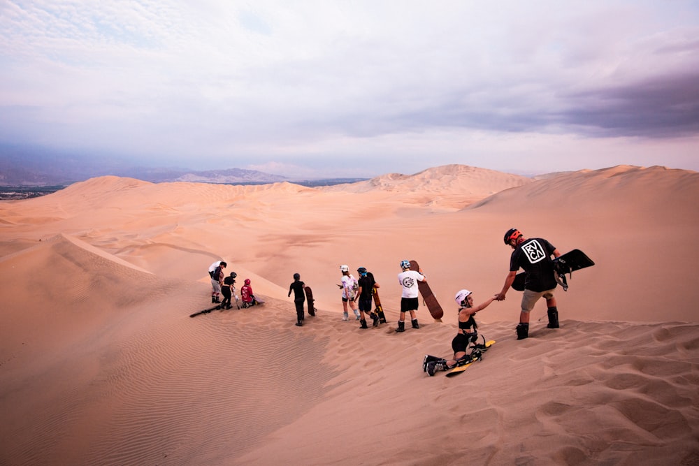 um grupo de pessoas em pé no topo de uma duna de areia