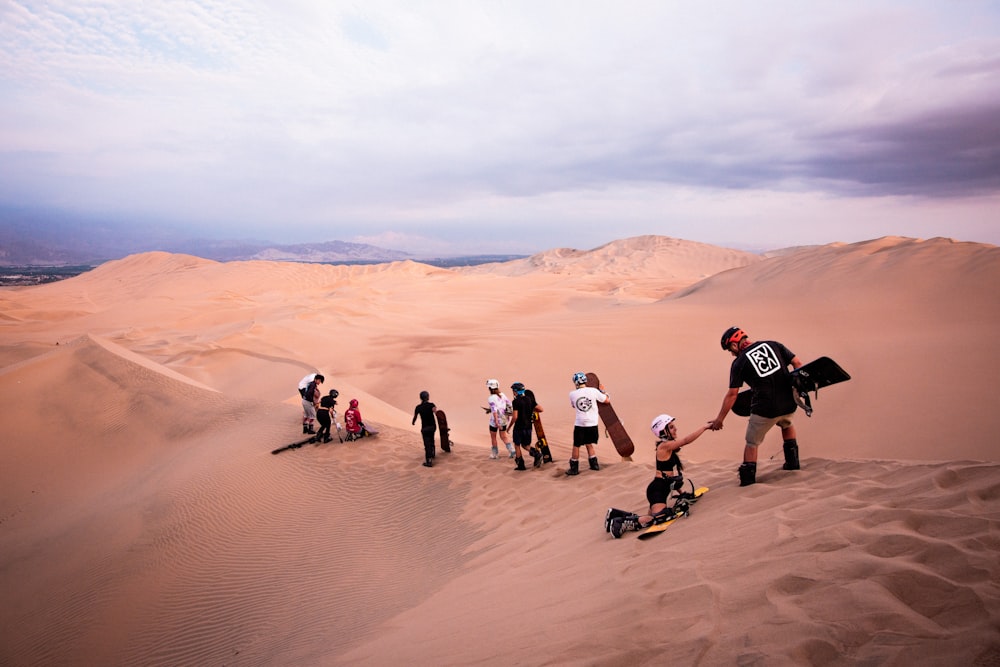 Un grupo de personas de pie en la cima de una duna de arena