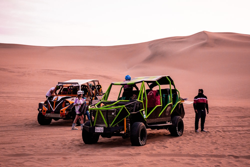 um grupo de pessoas em pé em torno de um veículo no deserto