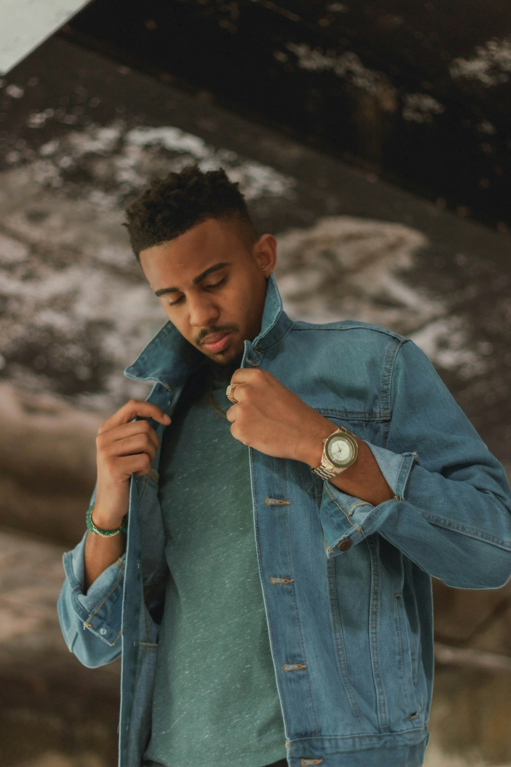 a man in a denim jacket adjusting his watch