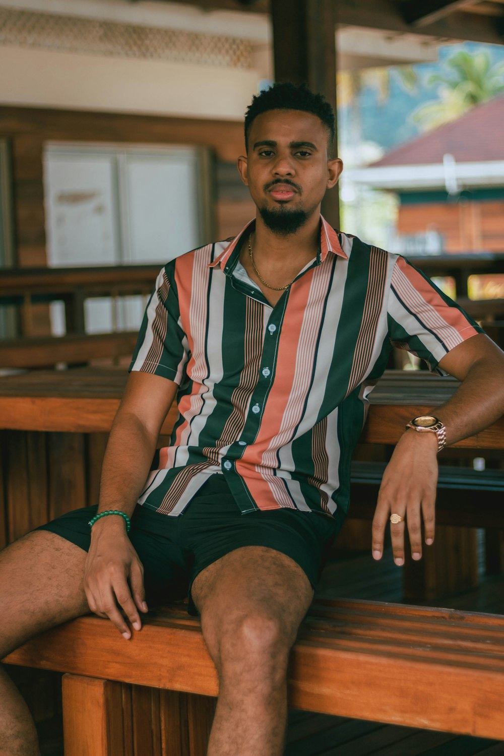 a man sitting on a wooden bench wearing a striped shirt