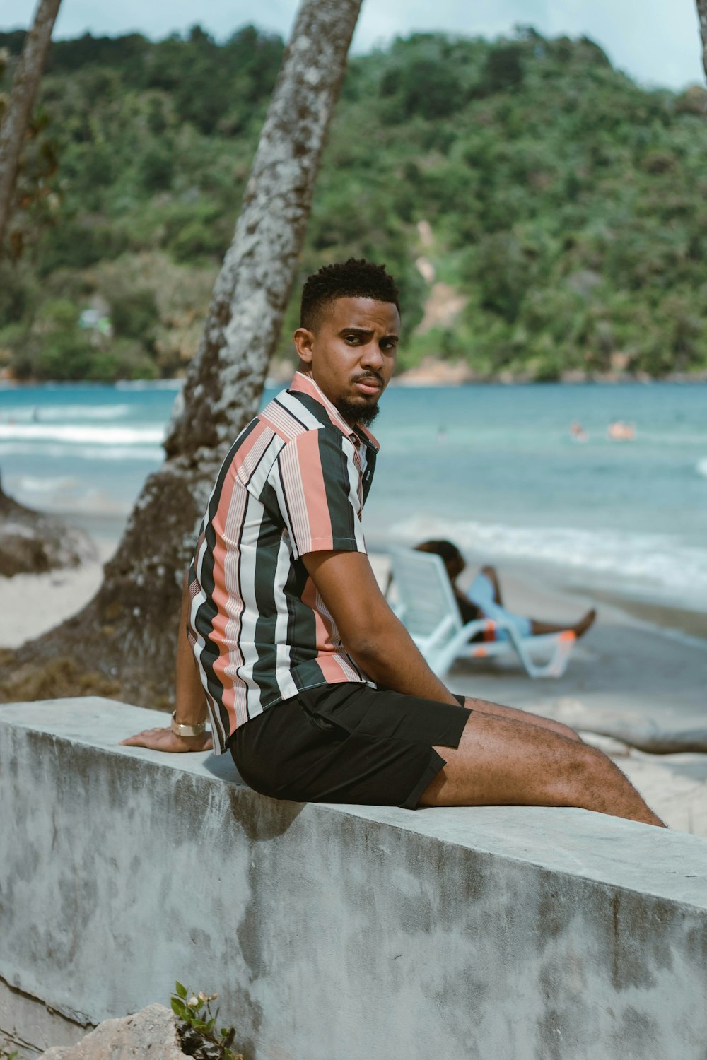 a man sitting on a wall near the beach