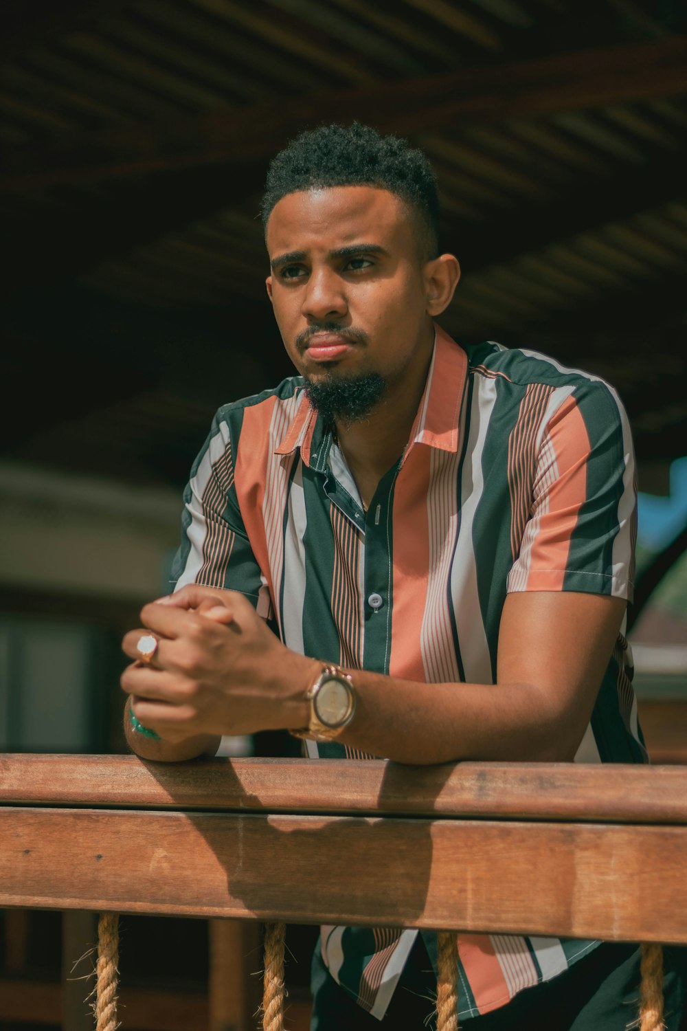 a man with a watch on his wrist leaning on a railing