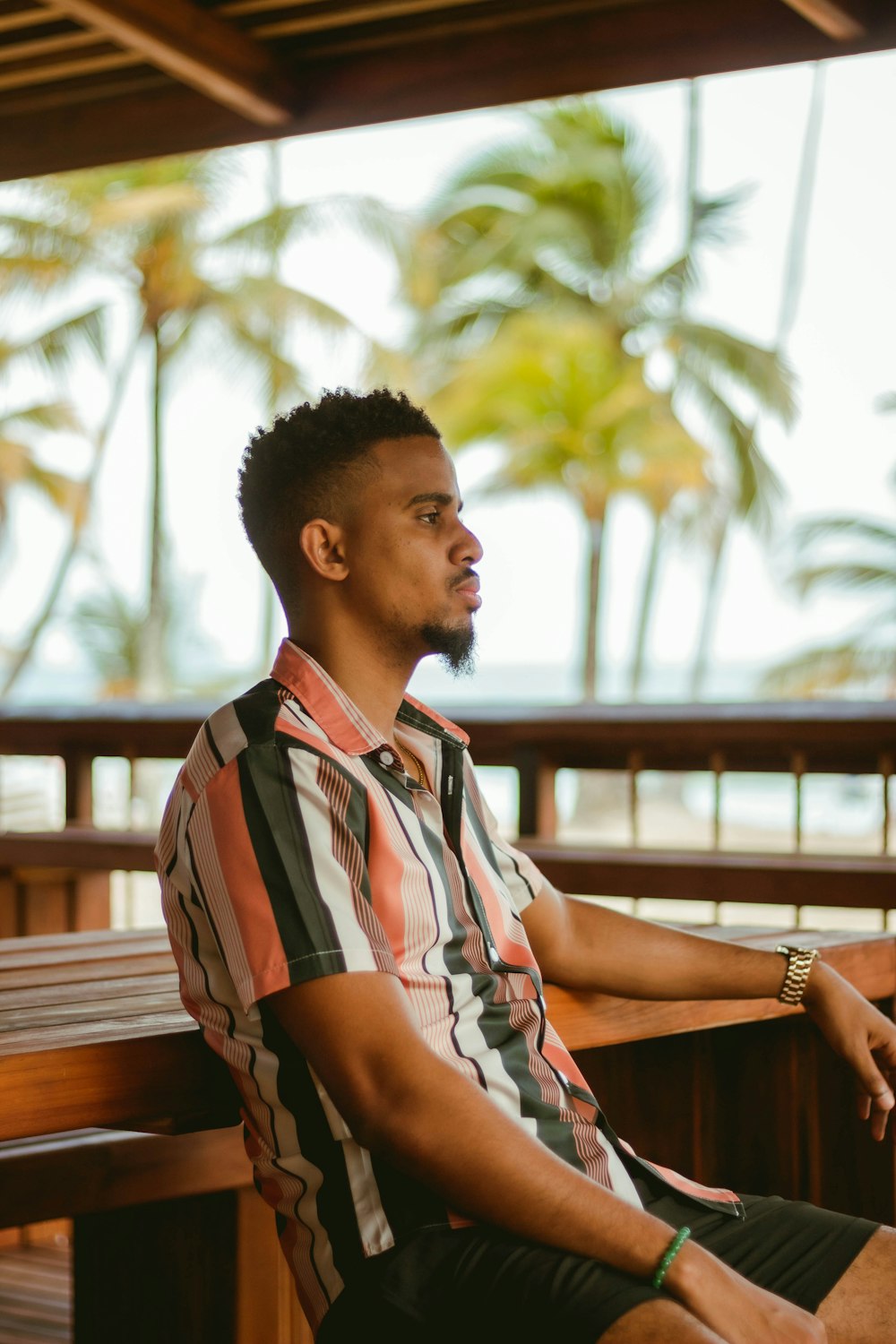 a man sitting on a wooden bench next to palm trees