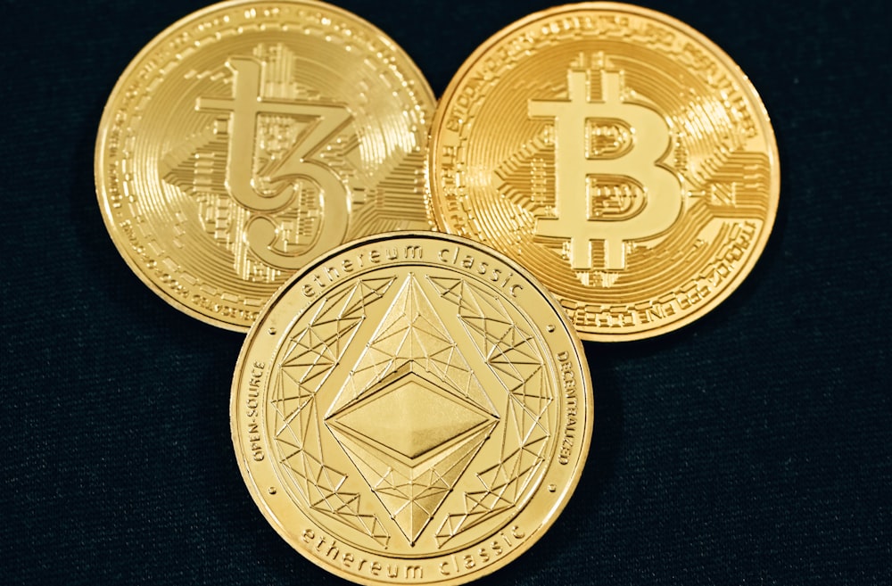 Drei goldene Bitcoins auf schwarzem Hintergrund