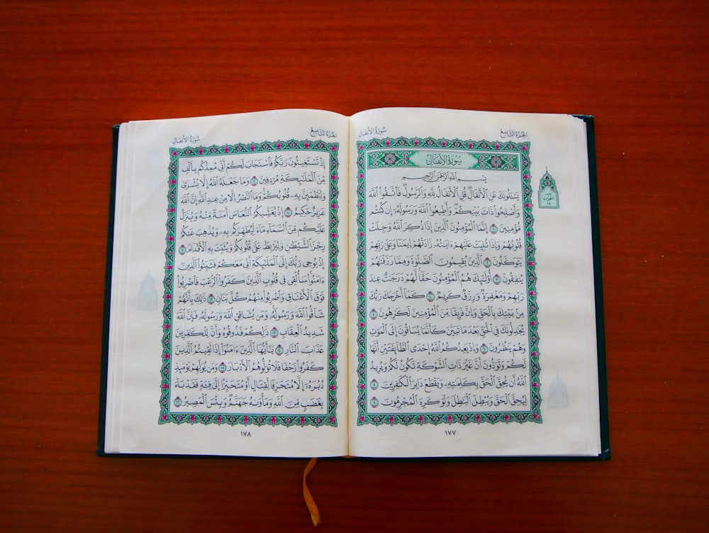 an open book with arabic writing on a wooden table