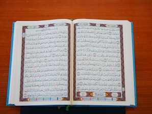 an open book with arabic writing on a wooden table