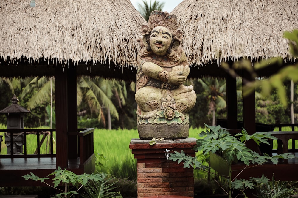 a statue in front of a thatched roof