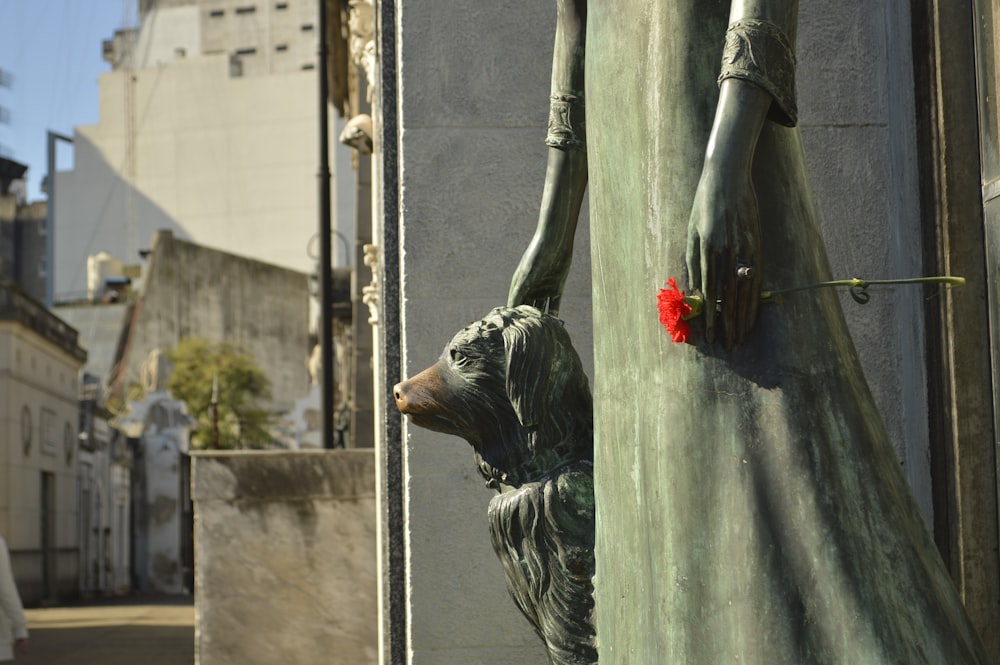 a statue of a woman holding a red flower