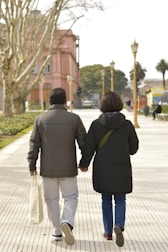a man and woman walking down a sidewalk holding hands