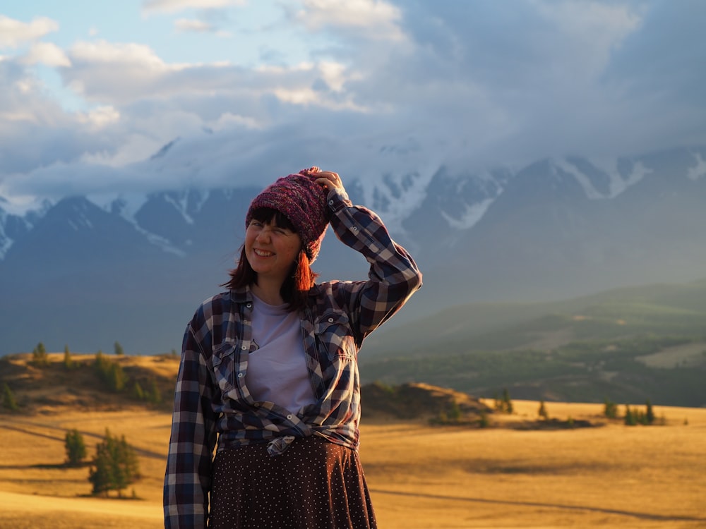 uma mulher em pé em um campo com montanhas no fundo
