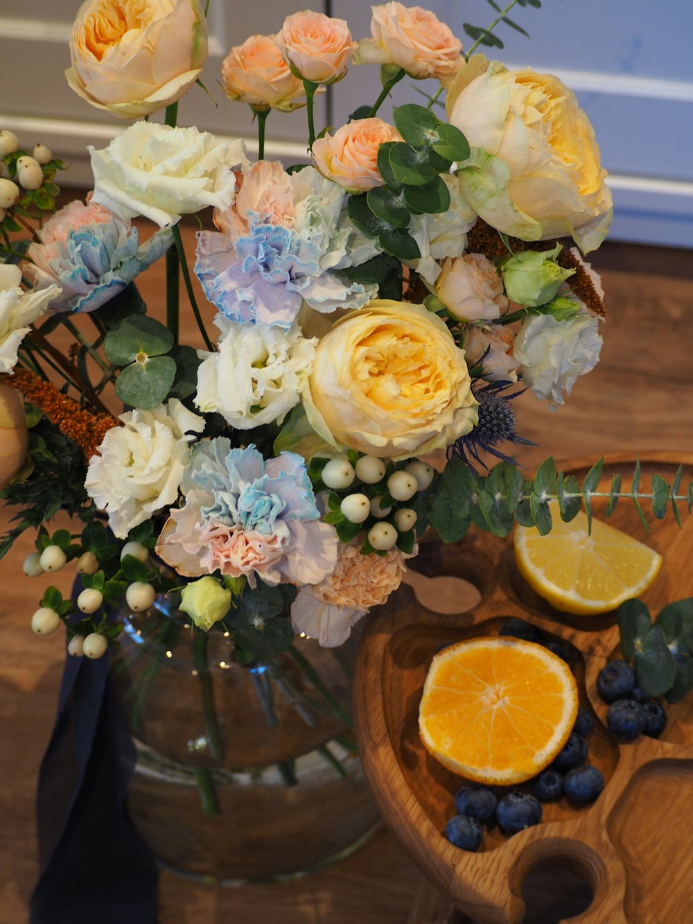 a vase filled with flowers and fruit on top of a table