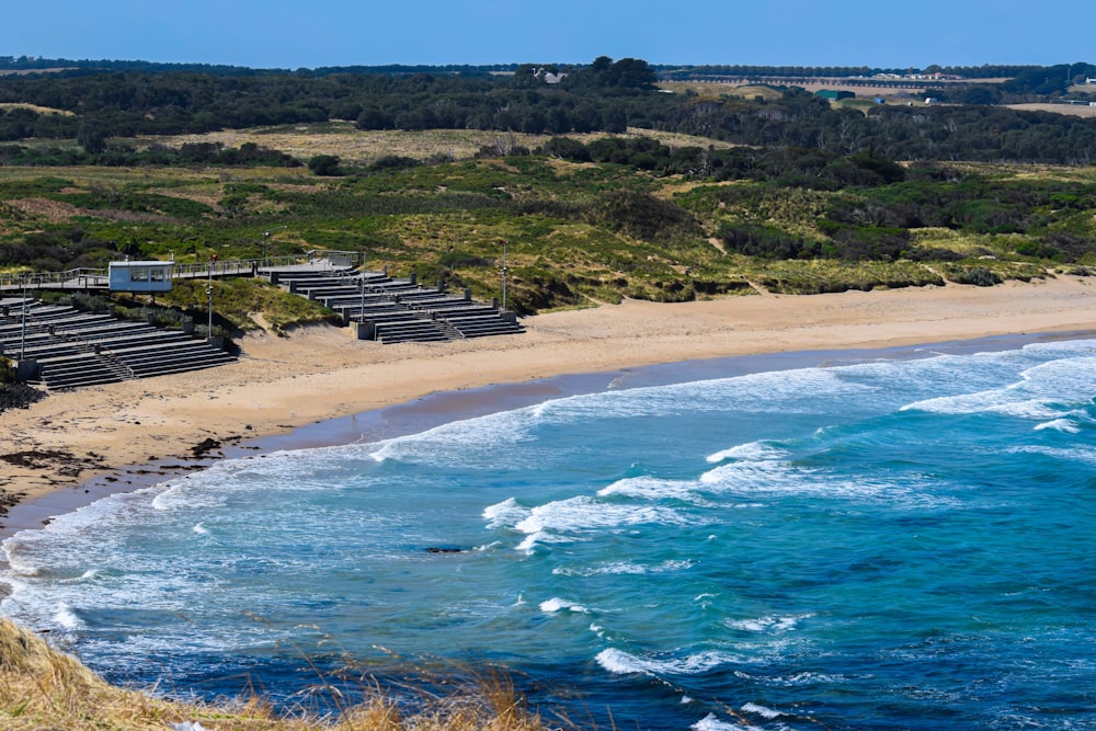 a sandy beach next to a lush green hillside