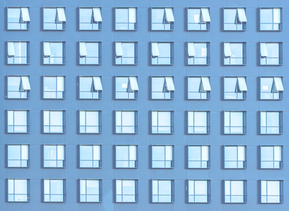 a blue building with many windows and a sky background