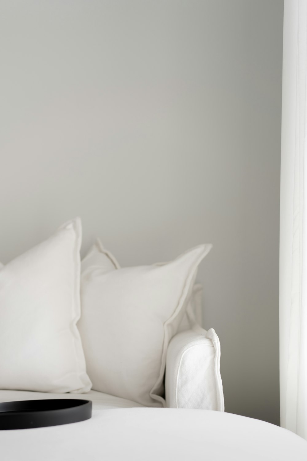 a white bed with white pillows and a black tray