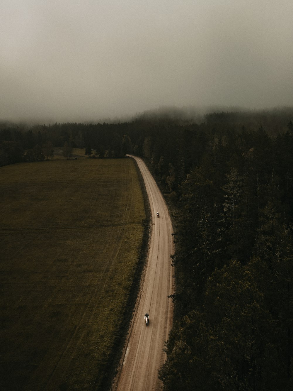 a car driving down a dirt road in the middle of a field