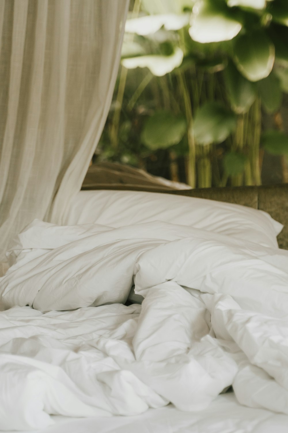 an unmade bed with white sheets and pillows