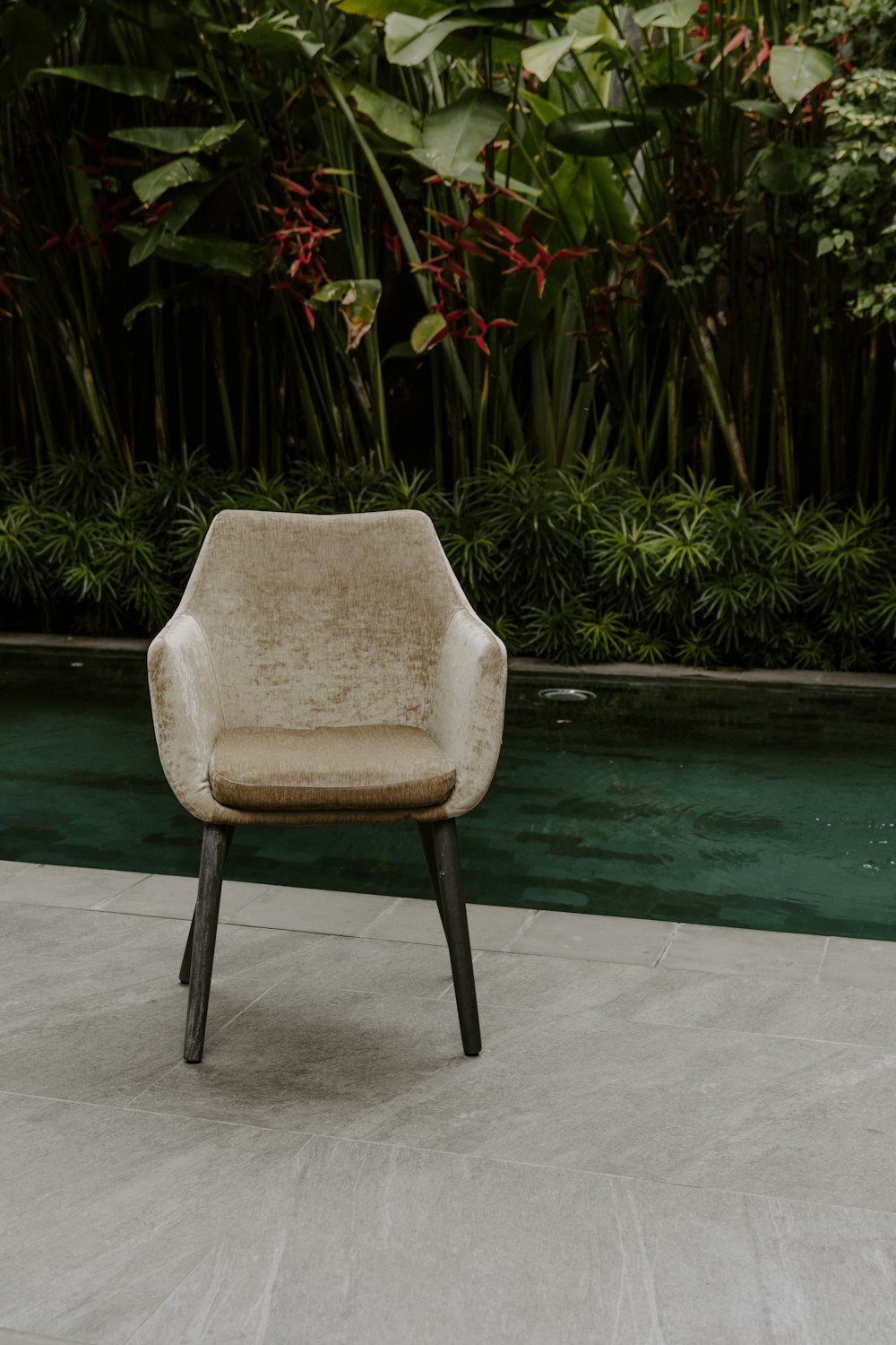 a chair sitting on top of a cement floor next to a pool