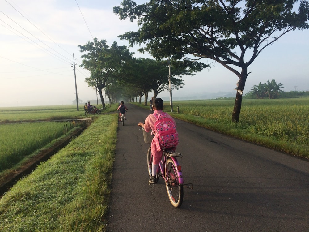 ピンクの自転車に乗って道を走る女性