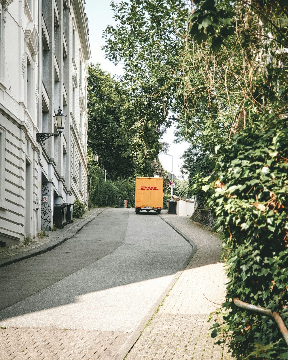 a yellow truck driving down a street next to tall buildings