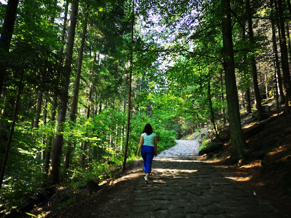 a woman is walking down a path in the woods