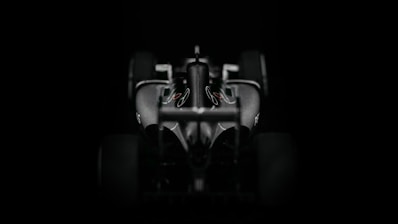 Close-up image of a Formula 1 car racing on a track, highlighting aerodynamic features.
