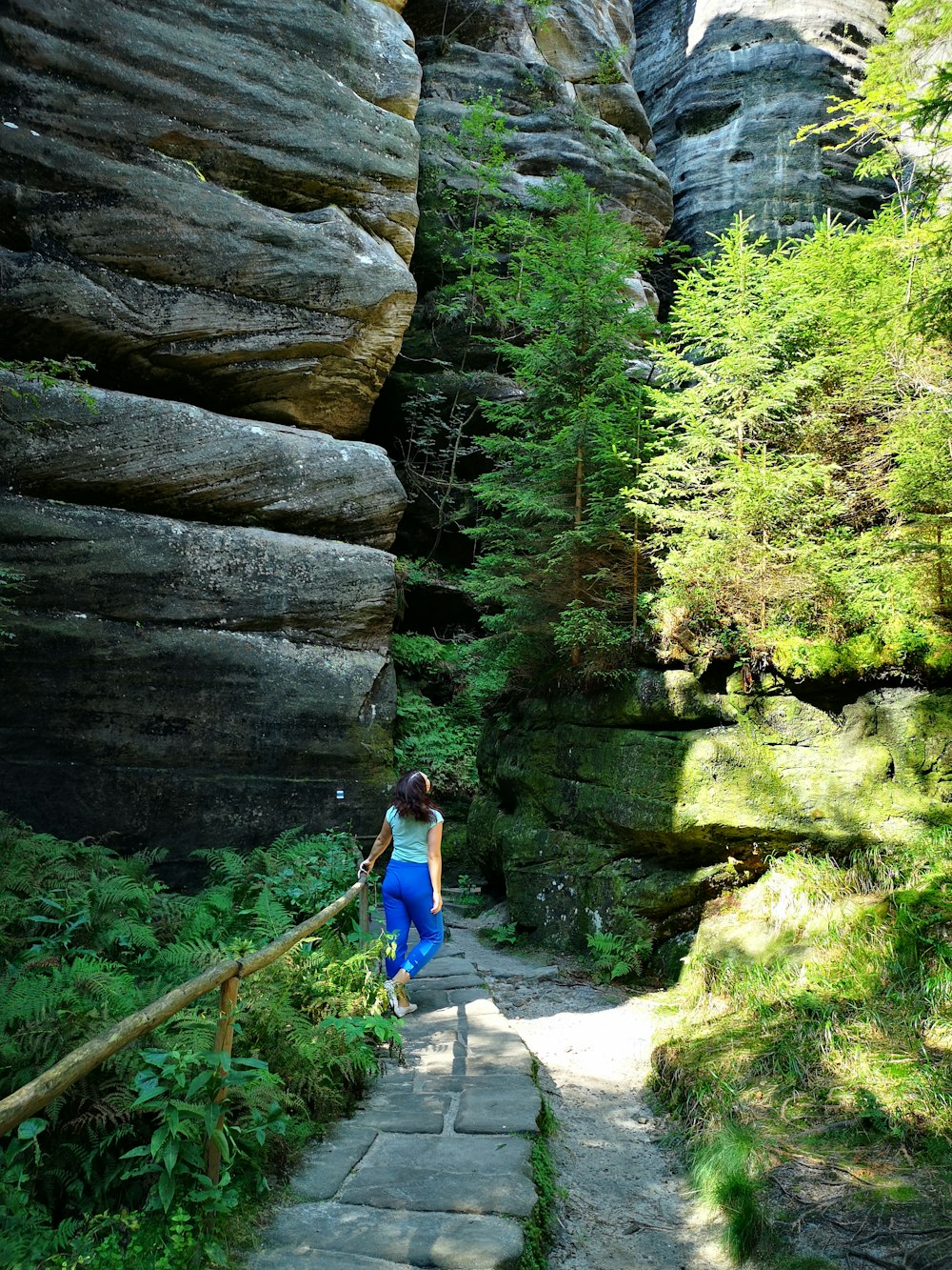 a woman walking up a stone path in the woods