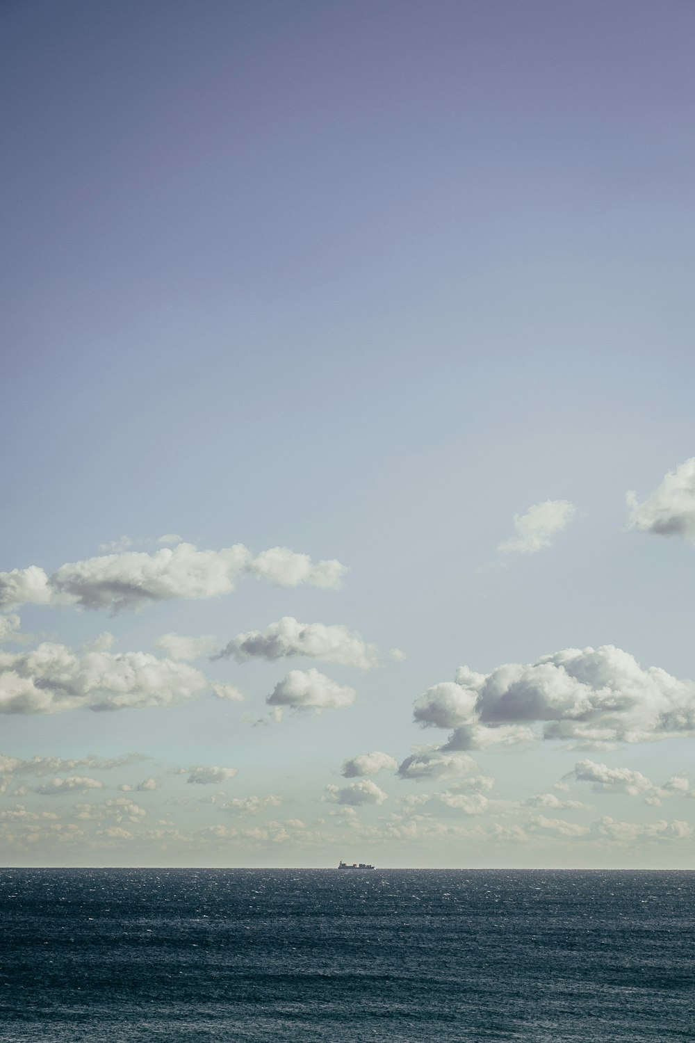 a large body of water sitting under a cloudy blue sky