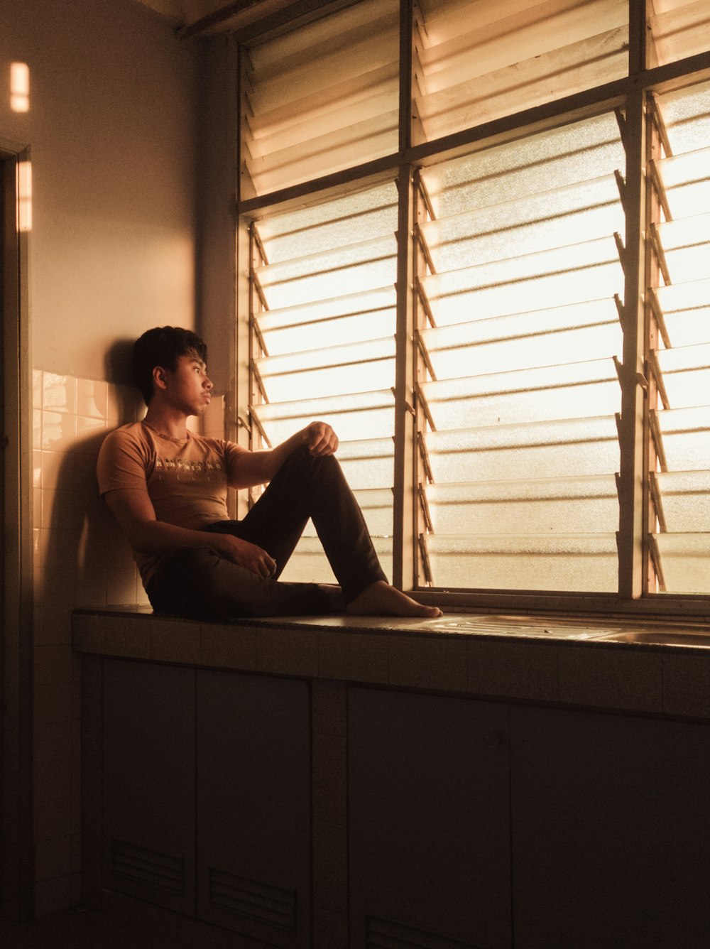 a woman sitting on a window sill looking out the window