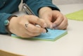 a person writing on a notepad with a pen