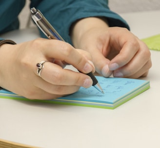 a person writing on a notepad with a pen