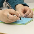 a person writing on a notepad with a pen