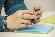a person writing on a notepad with a pen
