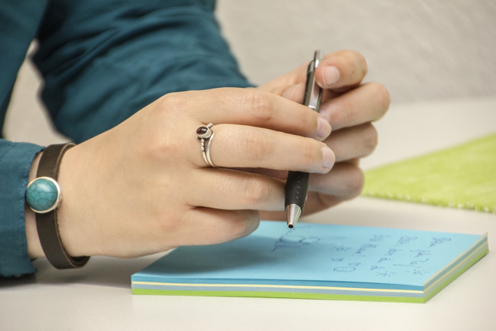 a person writing on a notepad with a pen