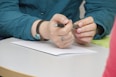 a person sitting at a table writing on a piece of paper