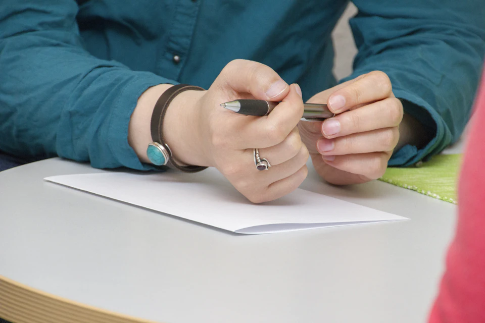 Hands taking notes on paper at a table