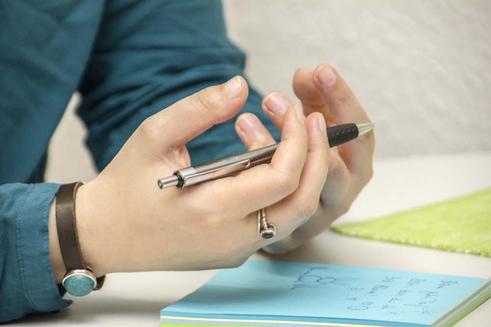 Eine Person, die mit einem Mobiltelefon an einem Tisch sitzt