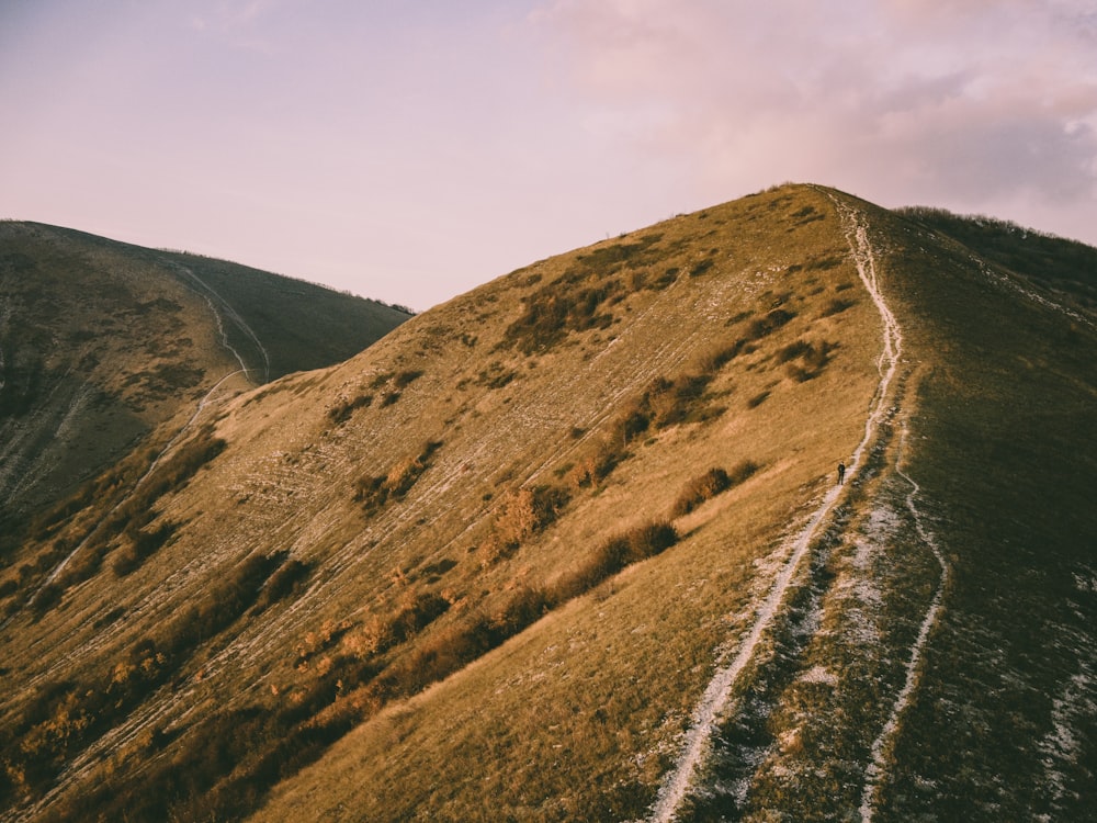 a grassy hill with a trail going up the side of it