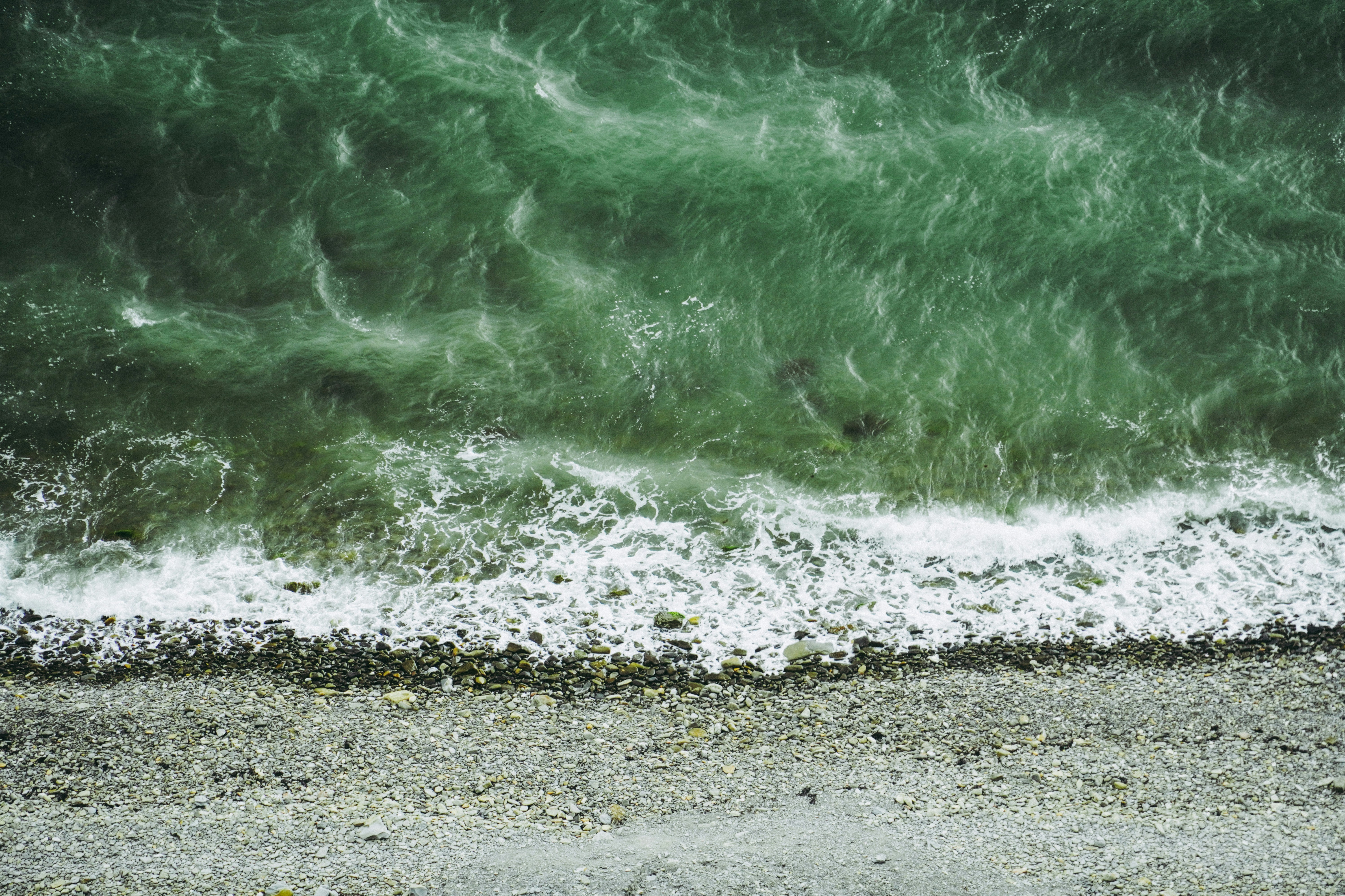 an aerial view of the ocean with waves crashing on the shore