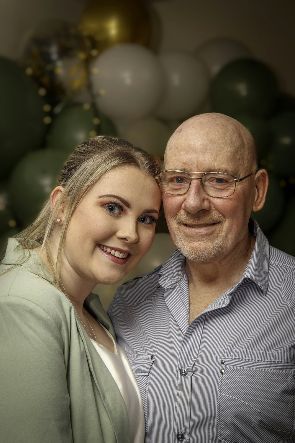 a man and a woman pose for a picture in front of balloons