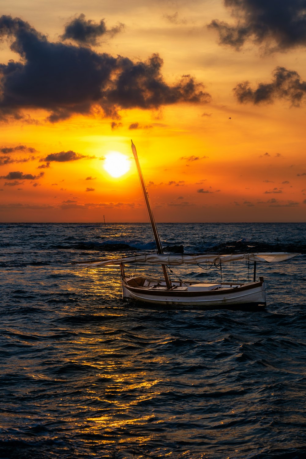 a sailboat in the ocean at sunset