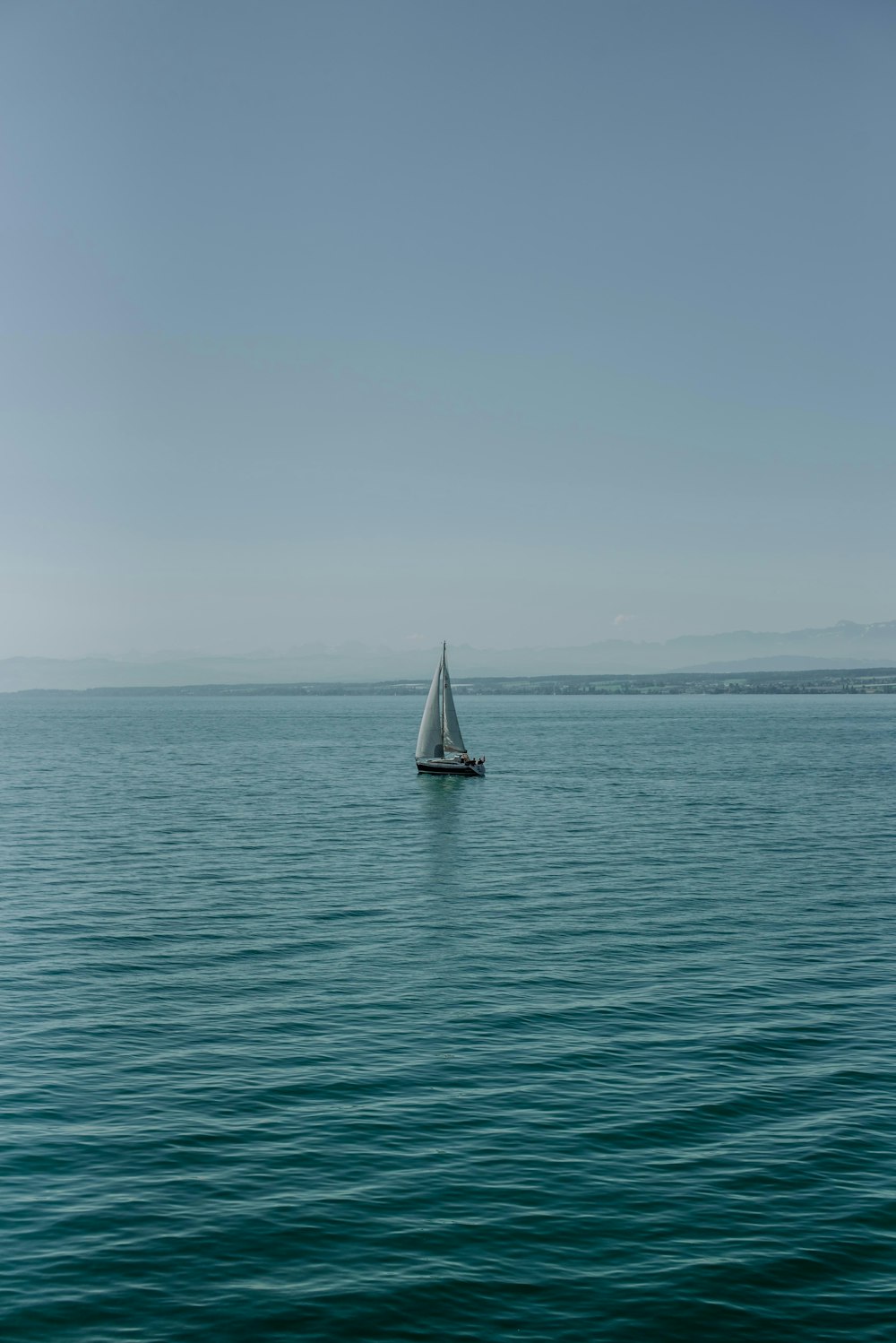 a lone sailboat in the middle of the ocean